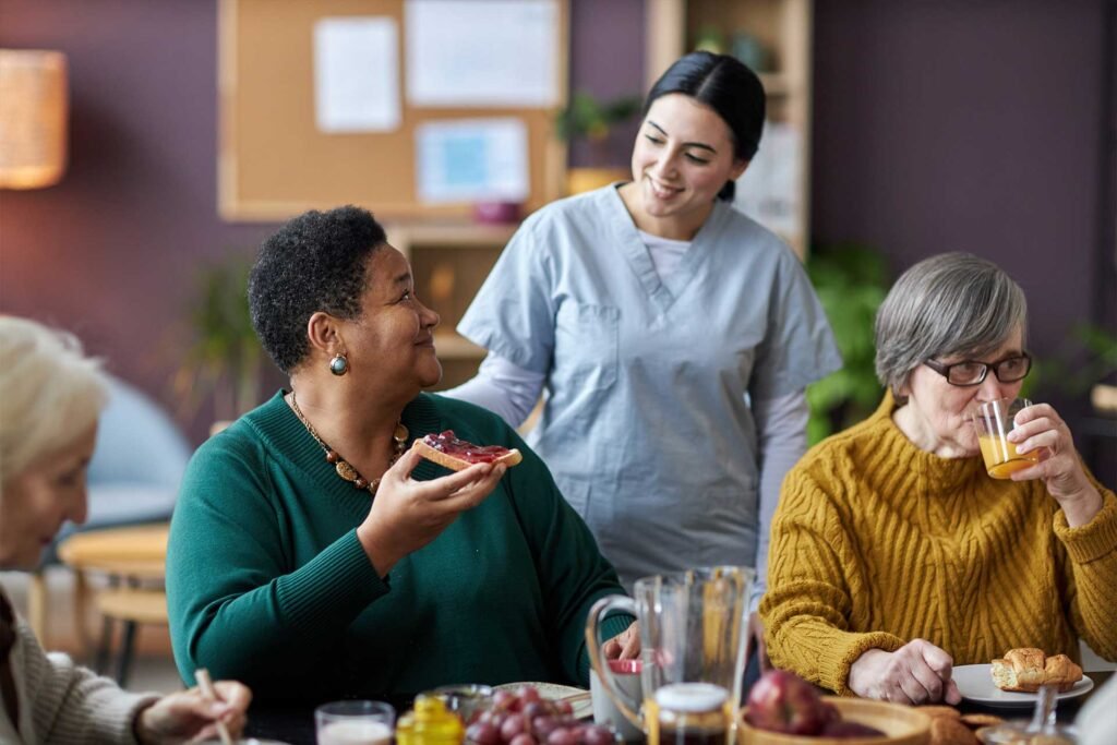 young-nurse-assisting-senior-people-during-breakfa-V26QWH7.jpg