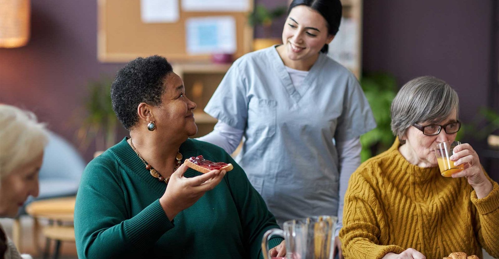 young-nurse-assisting-senior-people-during-breakfa-V26QWH7.jpg